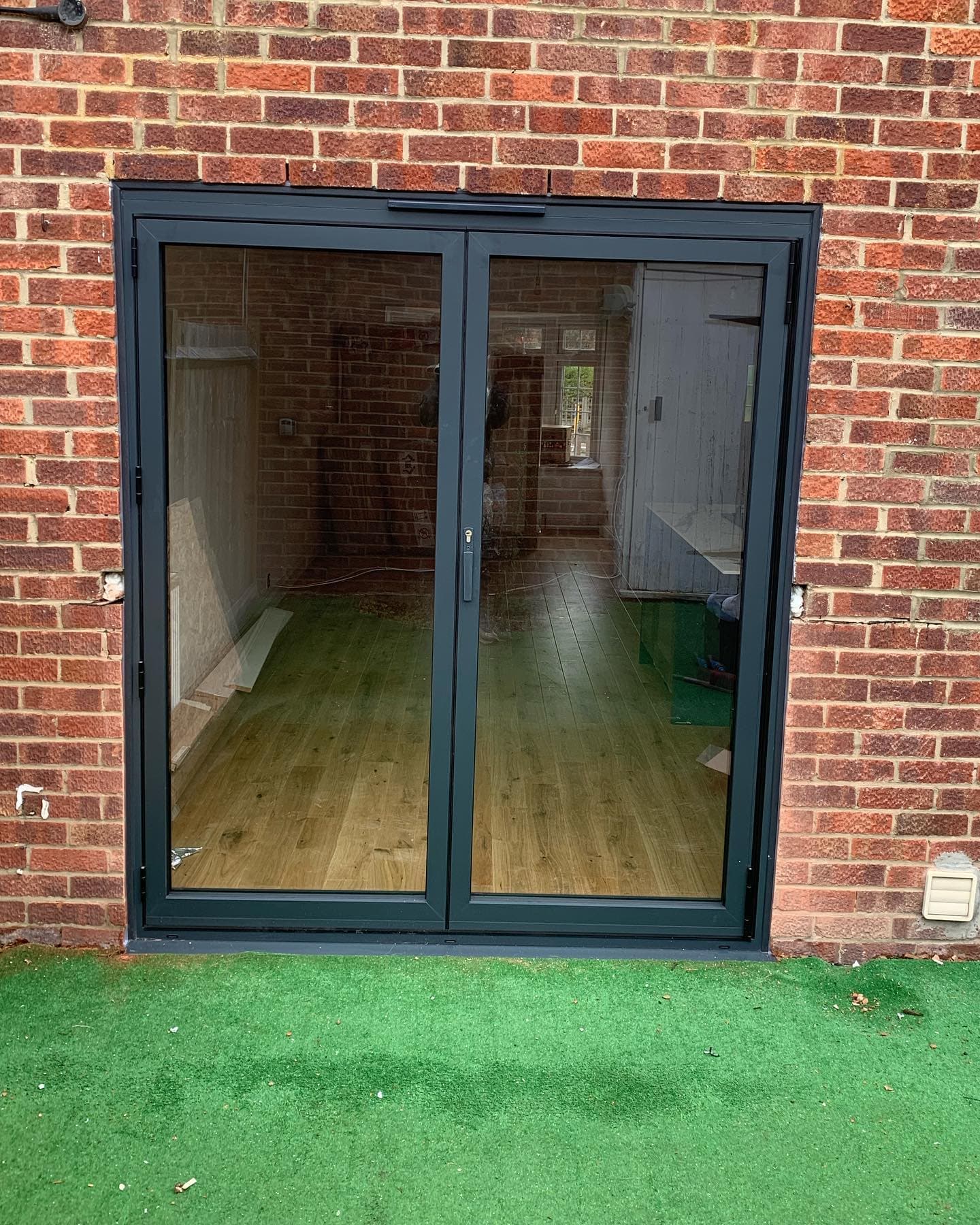 Anthracite aluminium bi-fold doors open to garden patio — Surrey, by A1 Window Construction Ltd