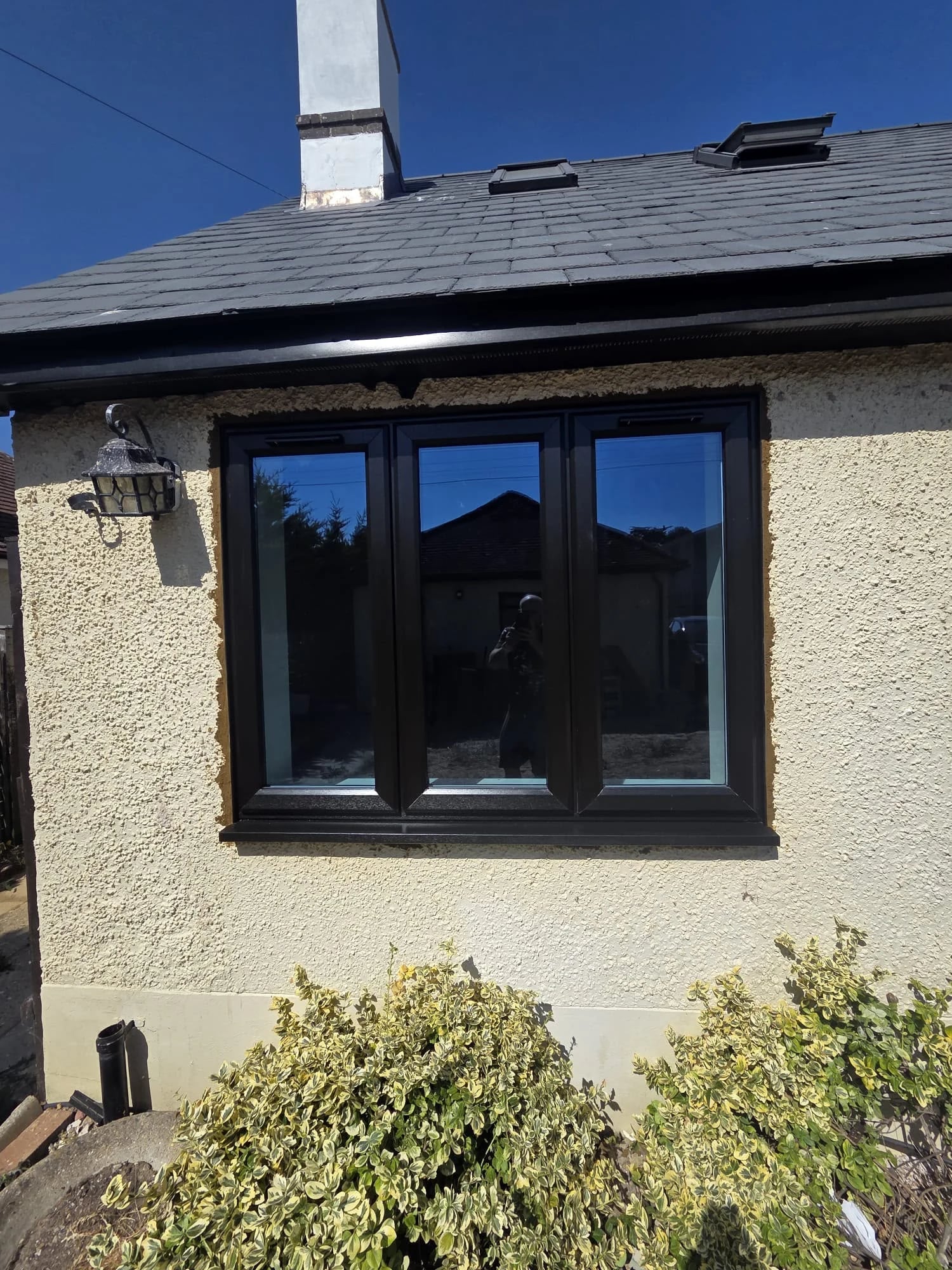 Three-light black casement under the roofline