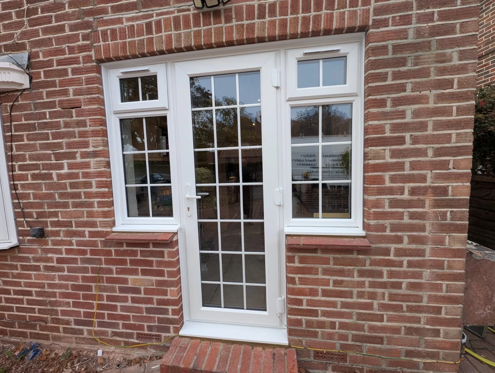 White Georgian-bar door with matching side windows in red brick — by A1 Window Construction Ltd