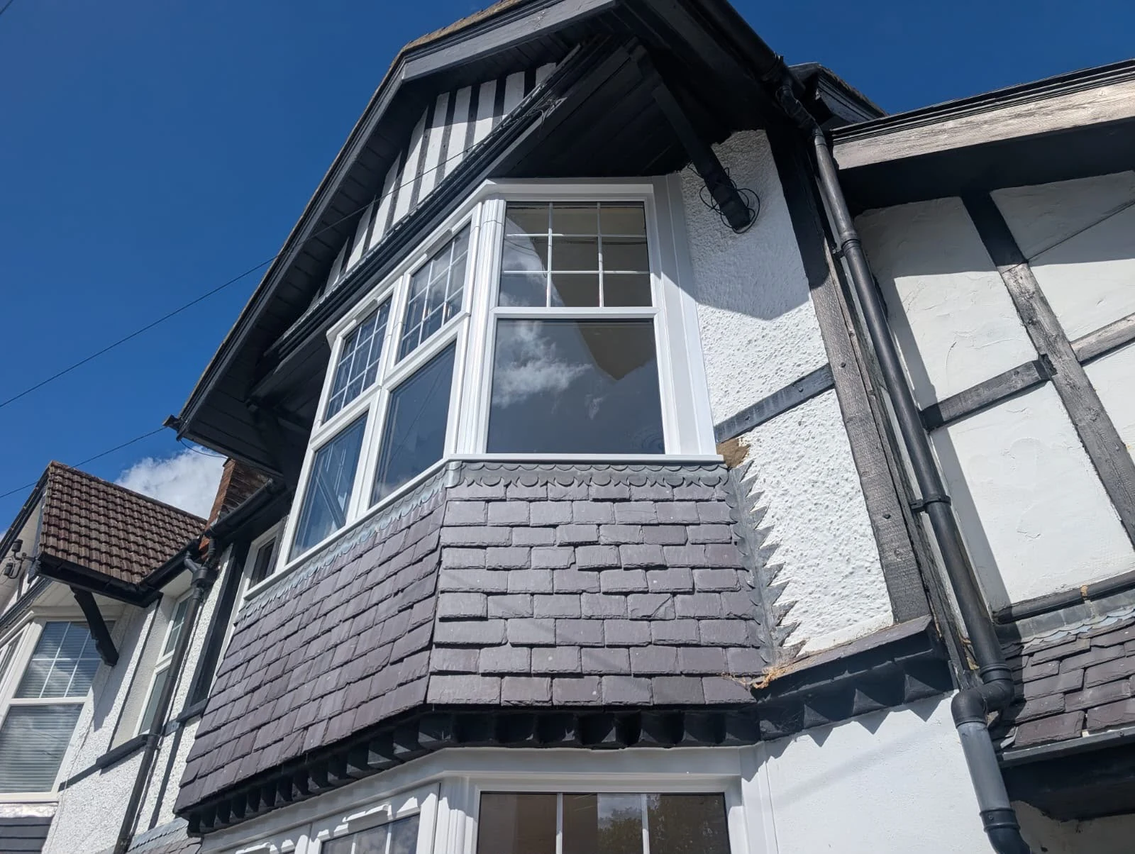 White Georgian-bar bay windows on a mock-Tudor house — by A1 Window Construction Ltd
